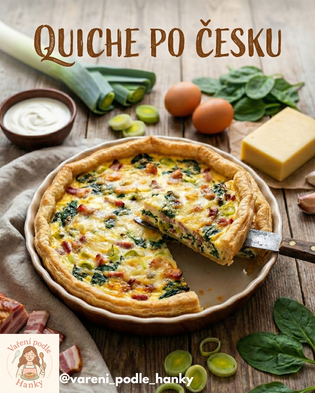 Quiche po česku: otevřený koláč se sýrem, špenátem a slaninou na dřevěném stole, zelenina v pozadí.